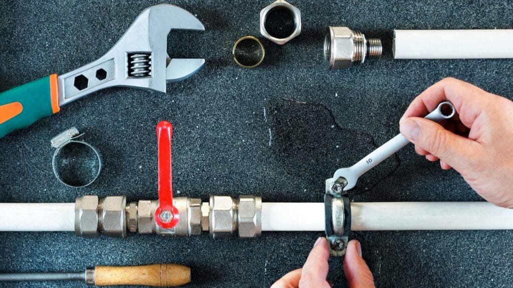 Plumber repairing a pipe valve with an adjustable wrench in Gainesville