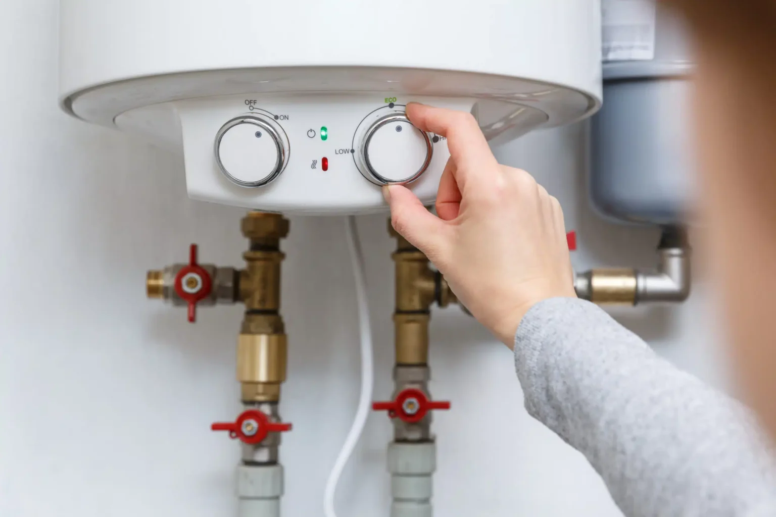 Homeowner adjusting the temperature controls on a water heater in Gainesville